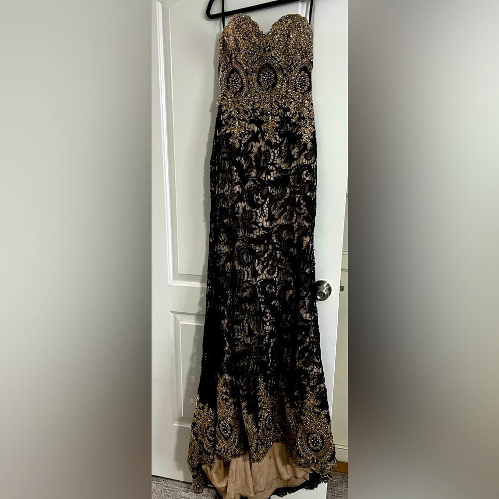 Sleeveless black dress with gems and a long tail.